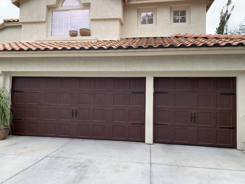 Two dark wood-effect carriage-style garage doors fitted to a tile-roofed Las Vegas home