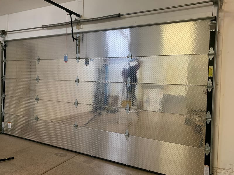 The inside face of an insulated garage door, showing the reinforcing strut and torsion bar