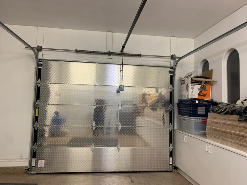 The inside of a fitted garage door with its opener rail and spring assembly overhead